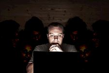 A cyber security threat – a man looks at his laptop, while people snoop over his shoulder